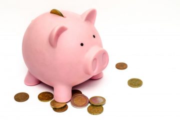 white background with pink piggy bank and coins laying around